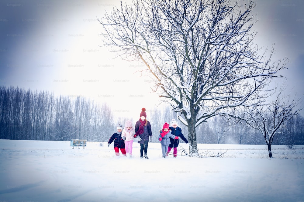 Cinco niños jugando juntos en la nieve. Espacio para copiar.