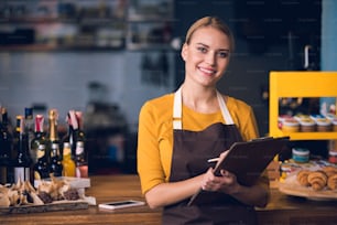 Ritratto di lavoratrice uscente che prende appunti mentre si trova vicino al bancone del caffè. Concetto di lavoro