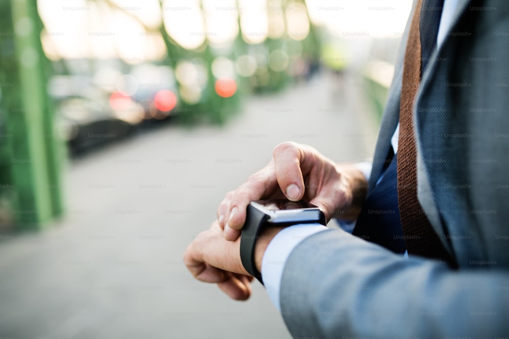 Empresário maduro irreconhecível com um smartwatch em uma cidade. Homem usando smartwatch como um smartphone. De perto.