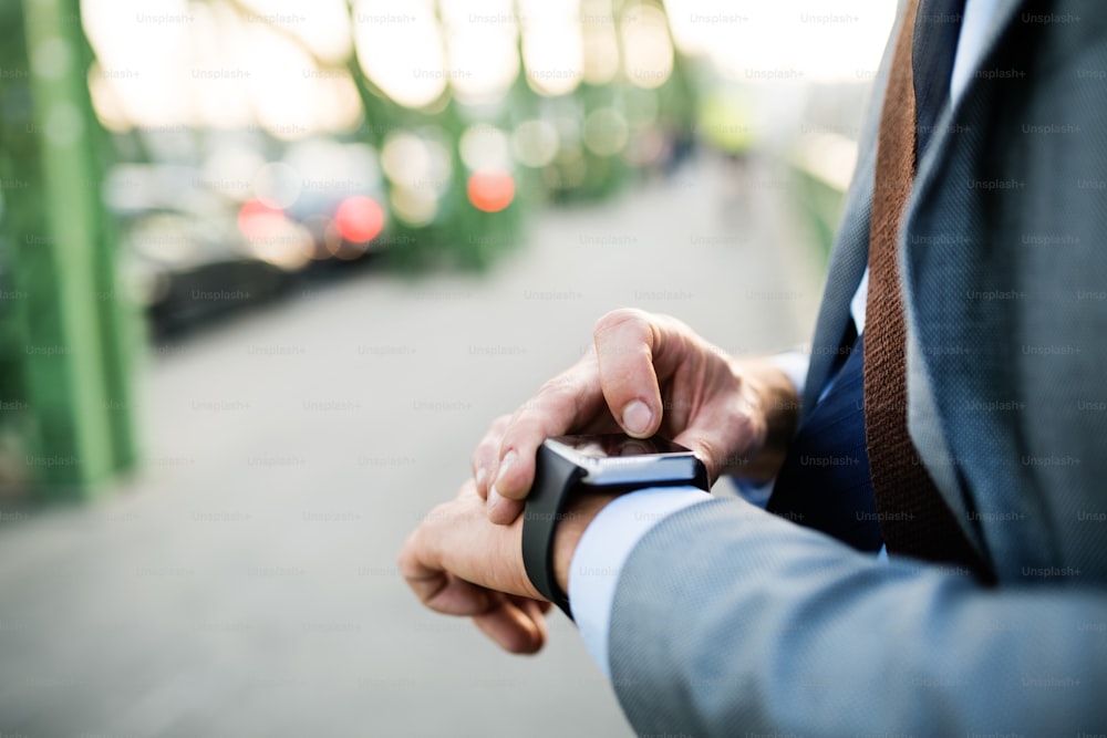 Unrecognizable mature businessman with a smartwatch in a city. Man using smartwatch as a smartphone. Close up.