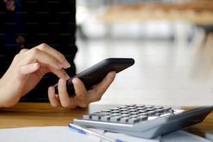 Closeup shot of an unidentifiable woman using a cellphone at office