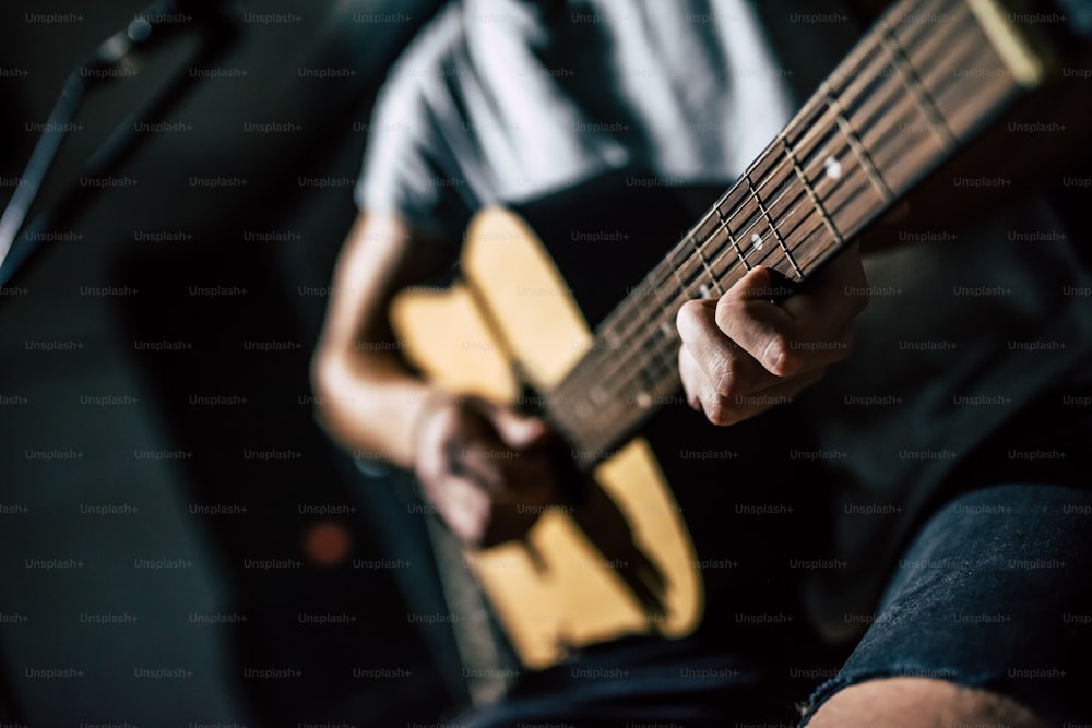 Cropped image of handsome young man on rehearsal base. Lyric singer with acoustic guitar.