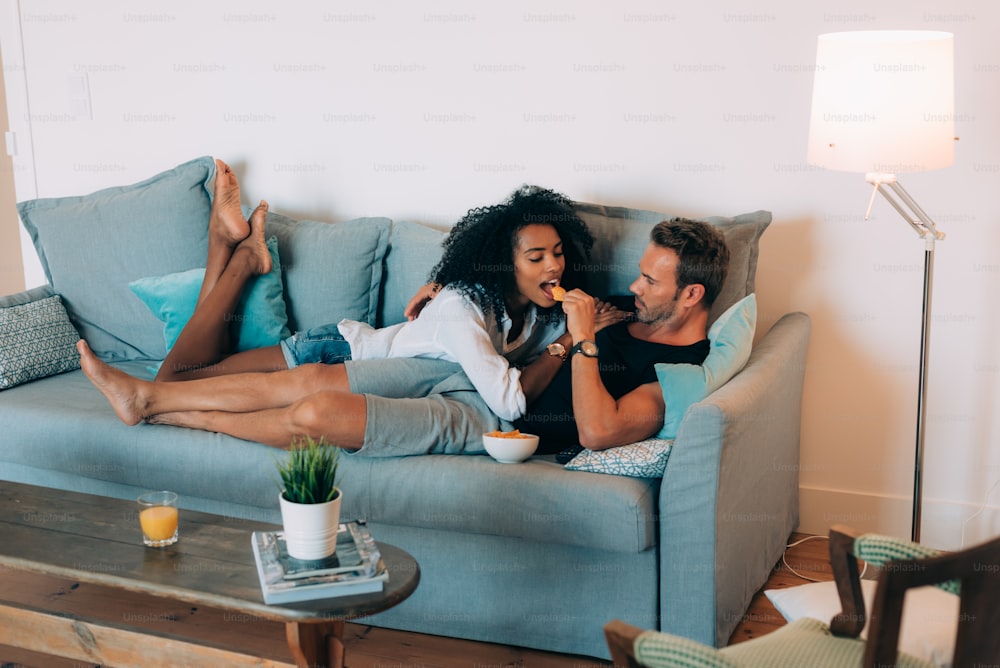 Glückliches junges Paar entspannt zu Hause auf der Couch und Spaß beim Spielen miteinander