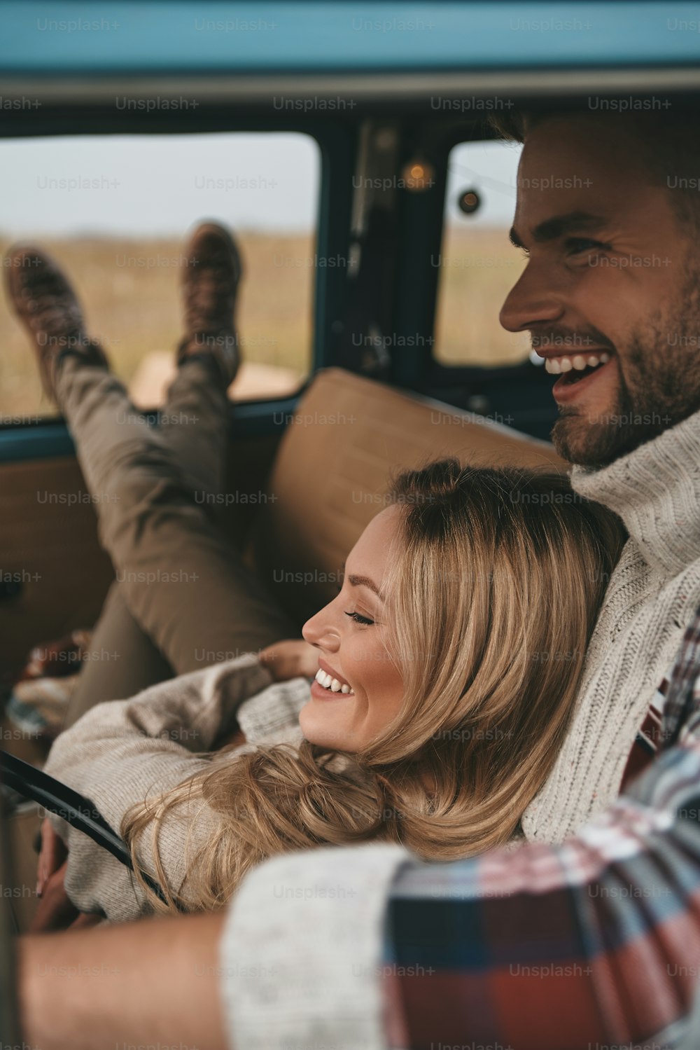 Giovane donna attraente che riposa e sorride mentre il suo fidanzato guida un mini van in stile retrò