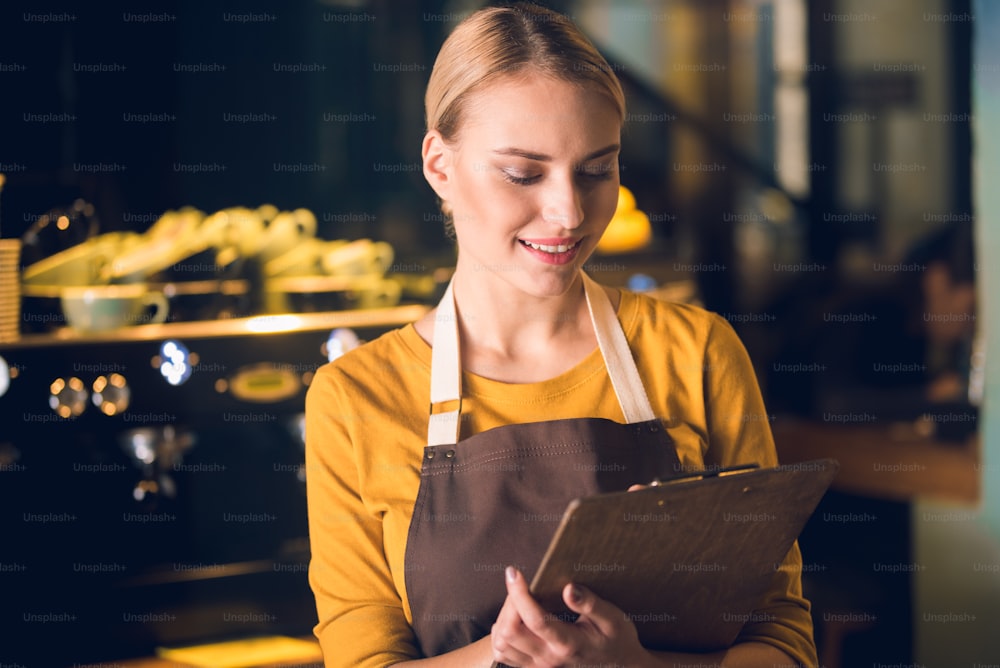 Portrait of cheerful worker looking through document while having job in cafe. Labor concept