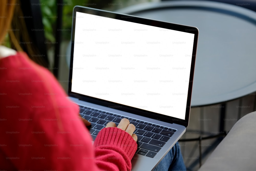 Foto da mulher usando e digitando no laptop com tela branca em branco.