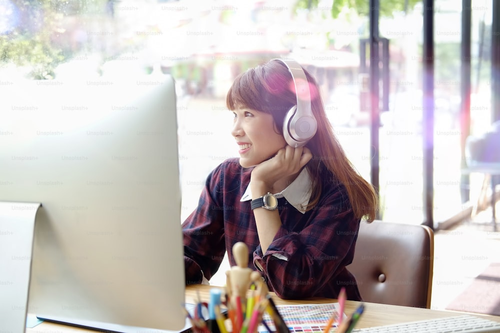 Happy woman using desktop computer while listening at studio office.