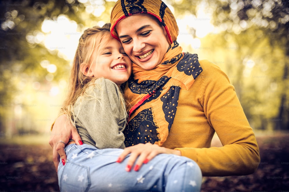Mother in hug with daughter sitting in park.