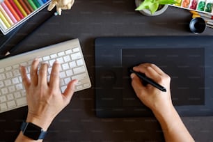 Top view Designer working with digital tablet and desktop computer at dark desk