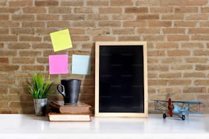 Mock up : Workspace wood desk and red brick wall. blank poster and vintage toy.