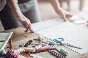 Cropped image of attractive female fashion designer is working in her workshop. Stylish woman in process of creating new clothes collection.