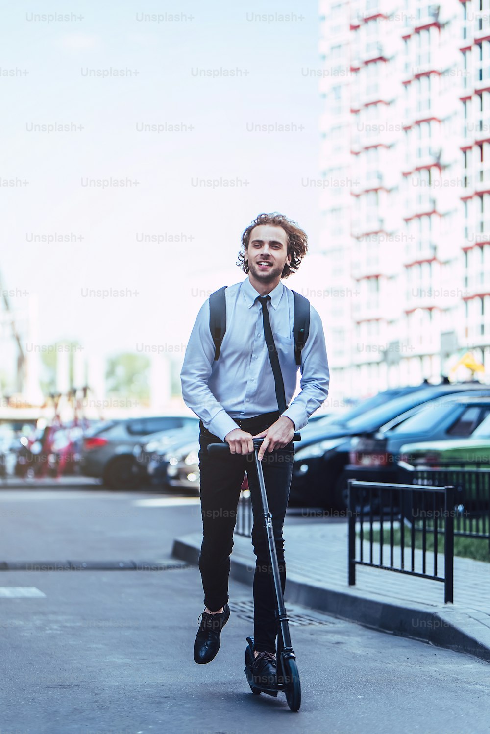 Young handsome businessman on street with kick scooter.