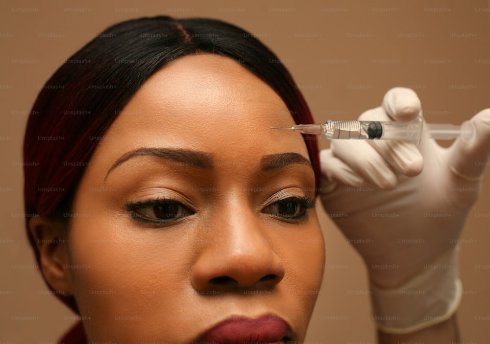 Portrait of middle age African woman applying filler injection. Close up.