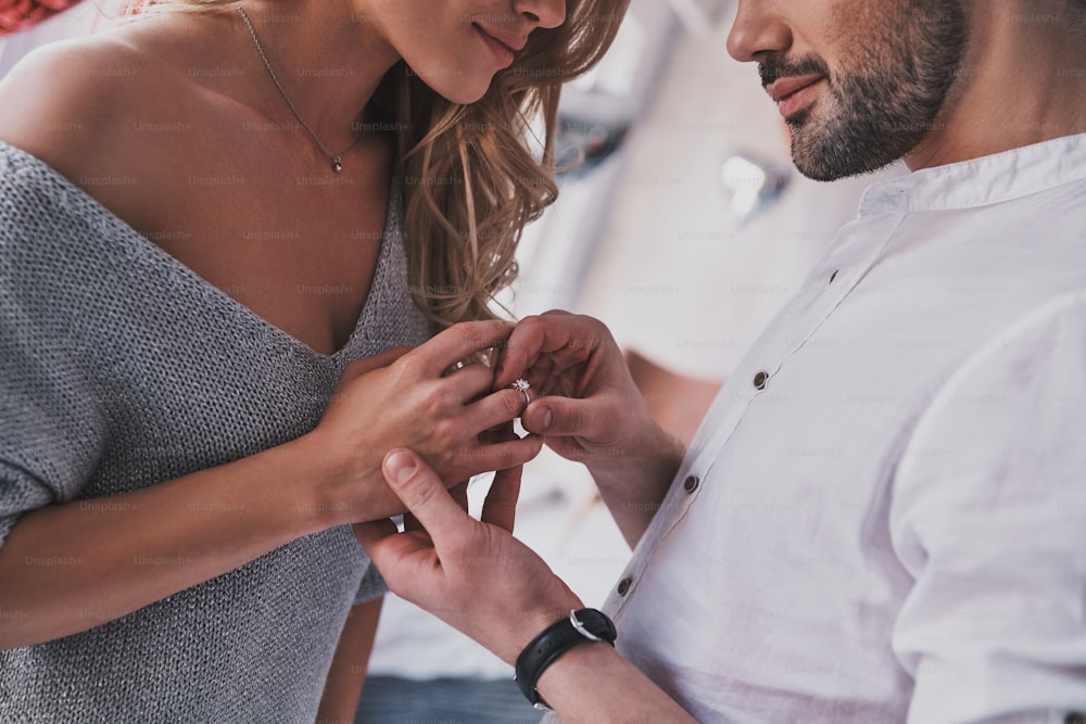 Primo piano di un giovane uomo che assume l'anello di fidanzamento al dito della sua ragazza mentre si trova in camera da letto