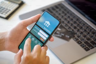 Mobile banking. Man holding smartphone showing online bank application on screen  at desk workspace in office. e-banking concept.