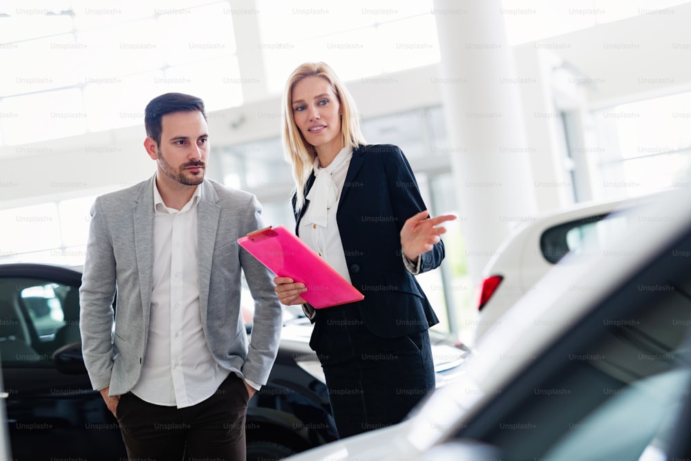 Professional salesperson selling cars at dealership to new buyer