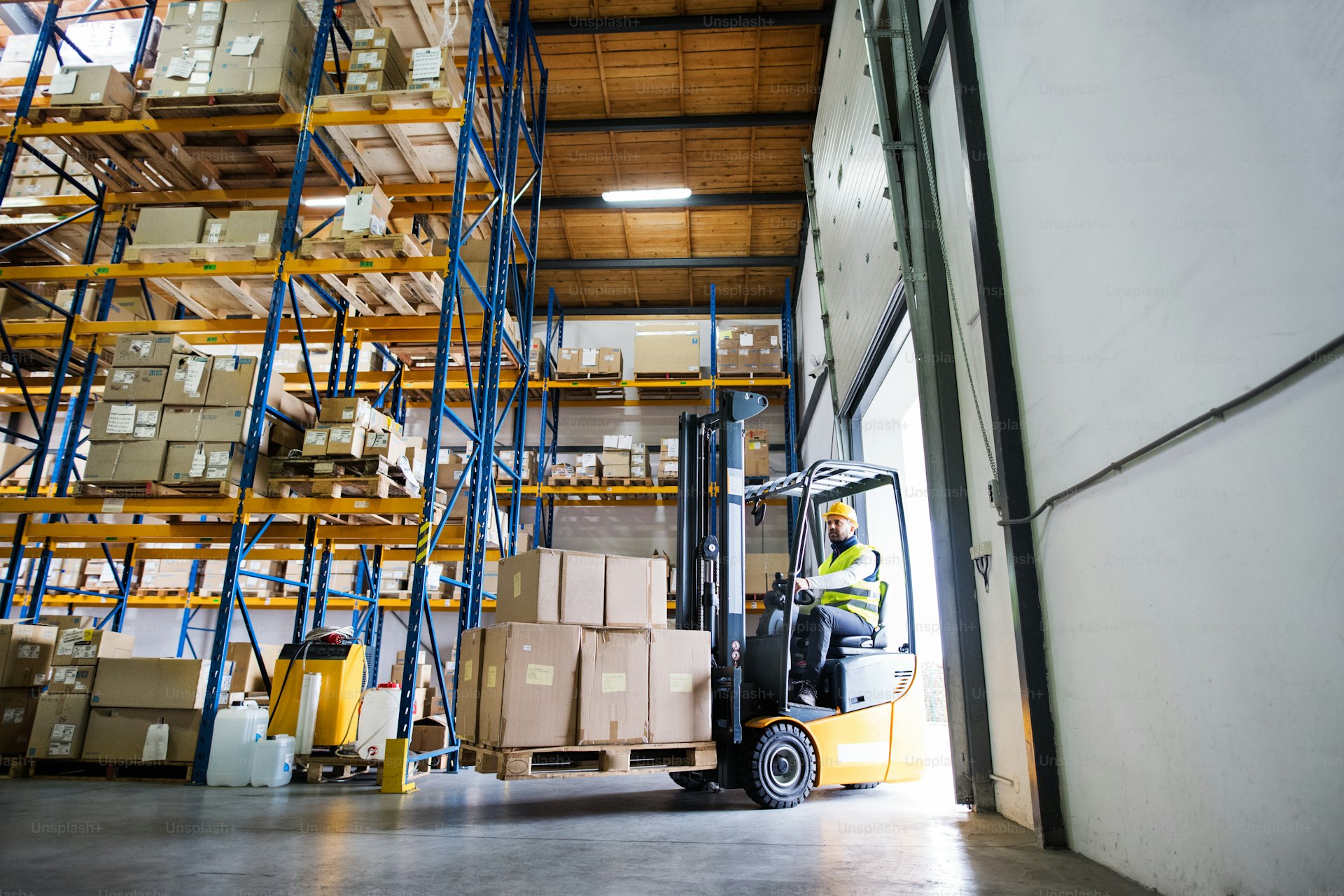 Forklift driver operating in a modern warehouse with safety gear