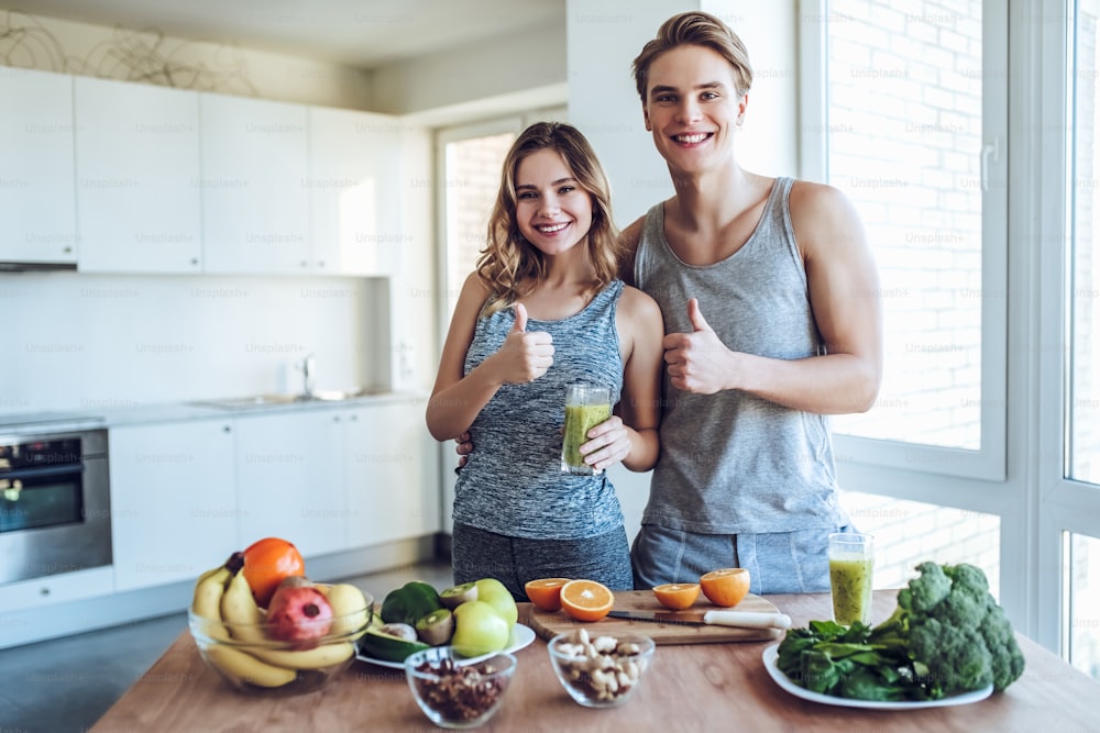 Happy sporty couple is preparing healthy food on light kitchen. Healthy food concept.