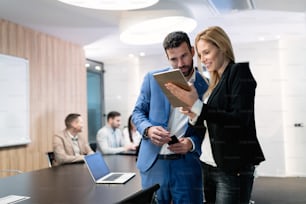 Attractive business couple working on tablet in modern office together