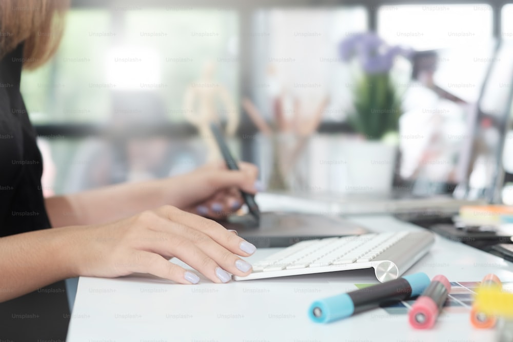 Femme de conception graphique créative travaillant sur une table avec un stylo souris et un PC de bureau.