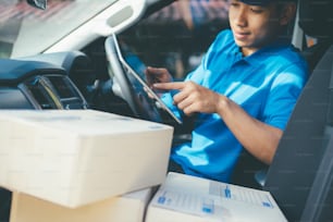 Deliver Service, Mailing and Logistic Concept.Young Delivery Man Checking Customer List On Tablet.