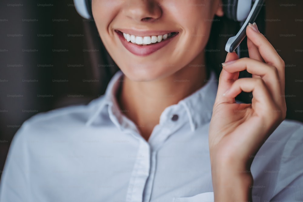 How can I help you?Cropped image of attractive female call center worker in headphones smiling.
