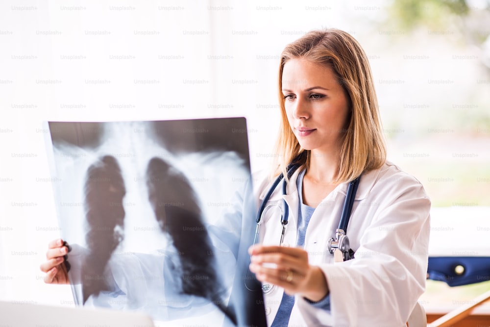 Young female doctor with laptop at the office desk. Doctor examining an x-ray.