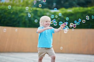 Happy adorable little boy playing with bubbles outdoors on a summer day