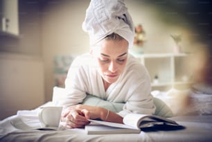 Frau liegt auf dem Bett und liest ein Buch. Aufschließen.