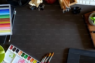 Designer workspace top view with essential elements on dark wooden board.