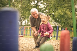 Grandfather and granddaughter playing on playground.