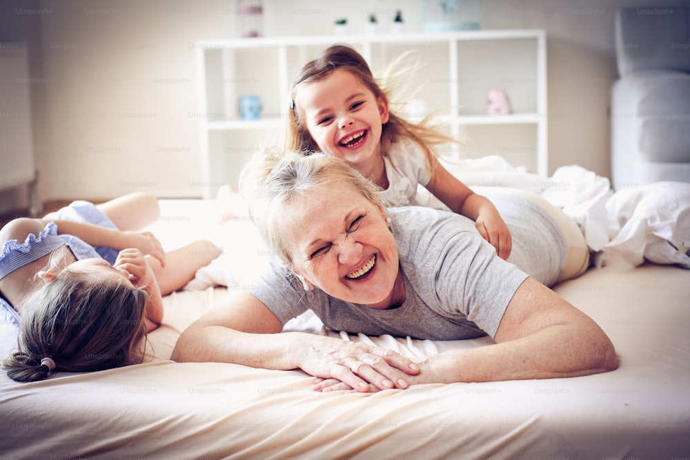 Grandmother enjoying in bed with her little granddaughters.