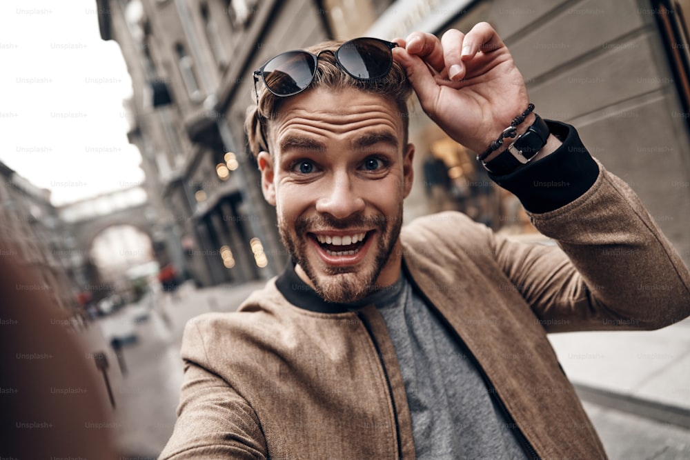 Selbstporträt eines gutaussehenden jungen Mannes in Freizeitkleidung, der lächelt und ein Gesicht macht, während er im Freien steht