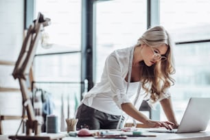 Attractive female fashion designer is working in her workshop. Stylish woman in process of creating new clothes collection.