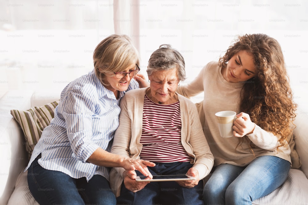 Un'adolescente, sua madre e sua nonna con un tablet a casa. Concetto di famiglia e generazioni.