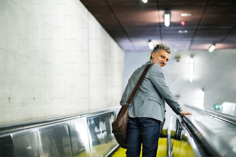 Belo empresário maduro em uma cidade. Homem em uma escada rolante na estação de metrô.