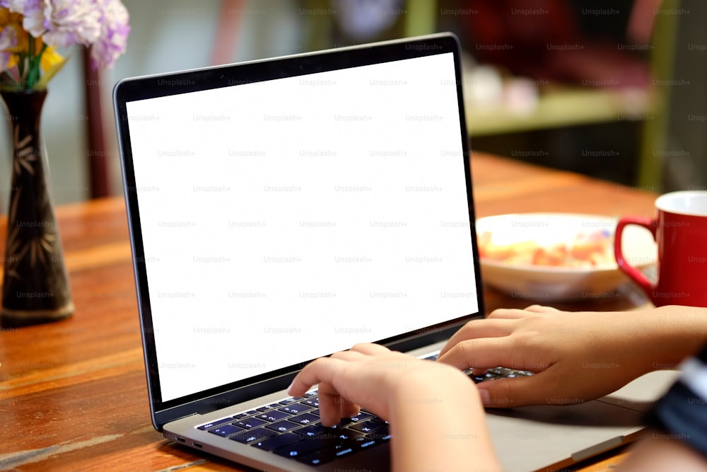 테이블에 빈 화면을 보여주는 노트북 컴퓨터를 입력하는 여성 손