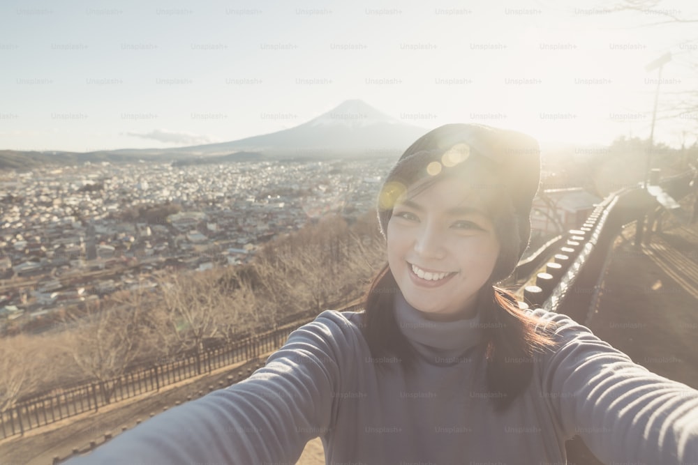Portrait of Attractive asian woman making selfie photo with mountain Fuji background on sunset