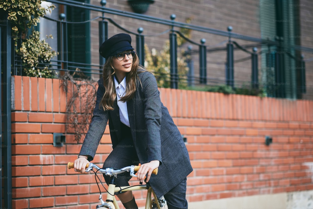 Joven mujer moderna montando en bicicleta en la ciudad.