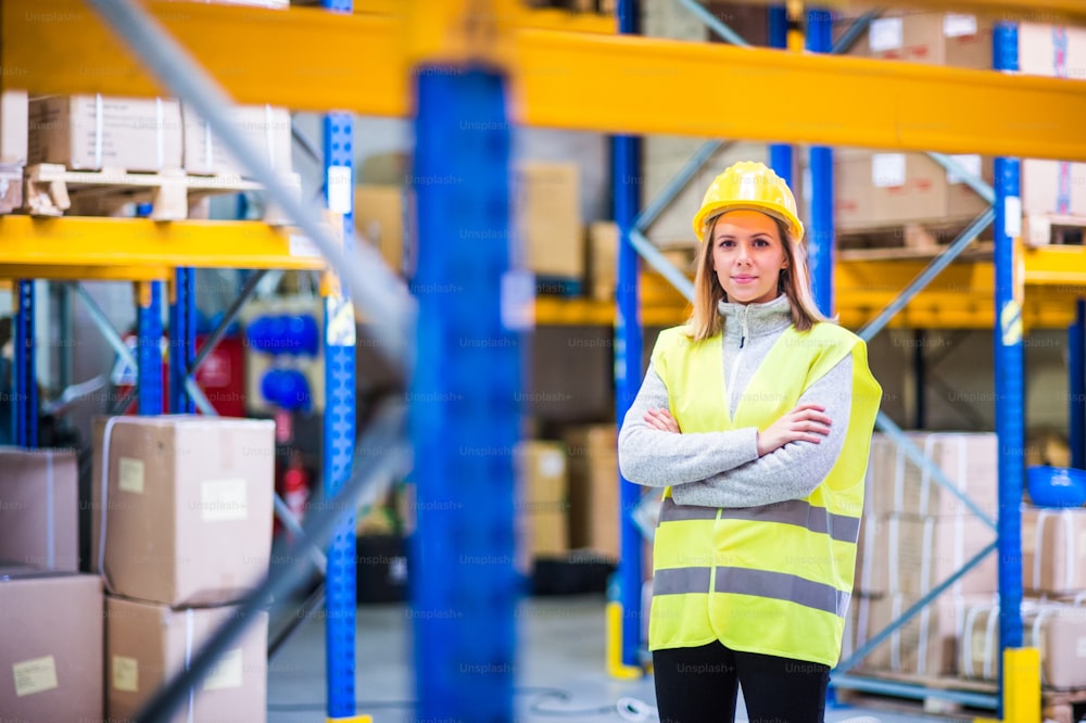 Portrait of a young woman warehouse worker or a supervisor, arms crossed.