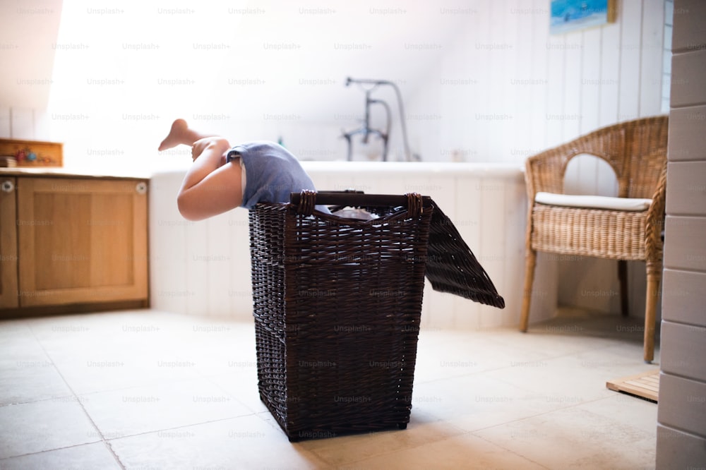 Little boy in a dangerous situation in the bathroom. A toddler in a laundry basket, legs sticking out.