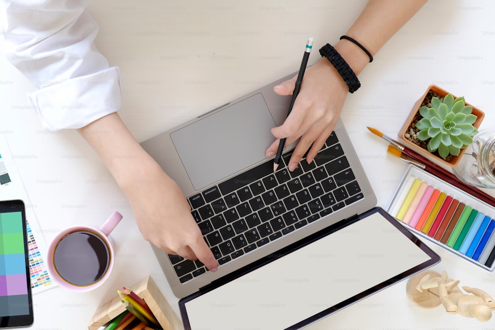 Female designer using laptop at creative studio desk.