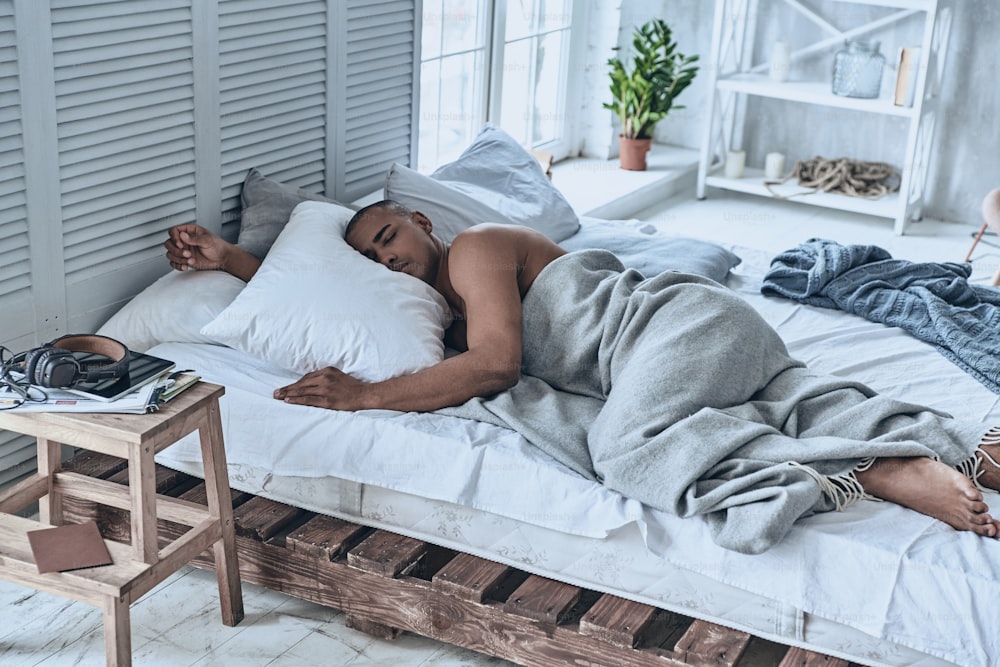 집에서 침대에 누워 있는 동안 자고 있는 젊은 아프리�카 남자의 상위 뷰