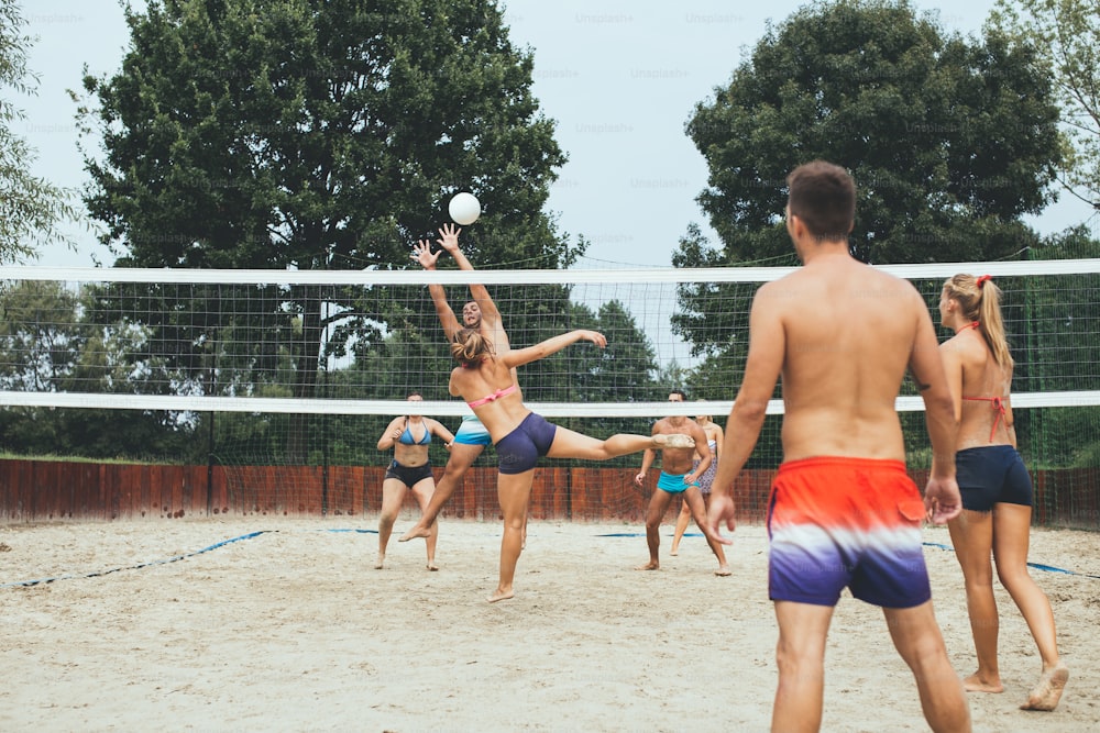 Grupo de jóvenes jugando voleibol de playa en un hermoso día soleado.