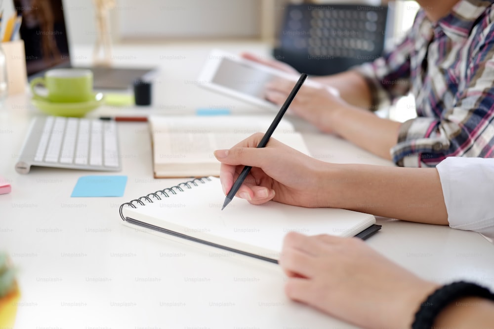 Startup da equipe: mulher escrevendo no caderno e discutindo detalhes no local de trabalho