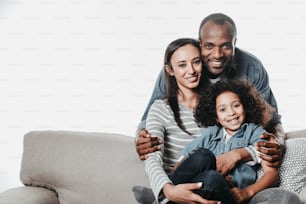 Portrait of african family looking at camera with joy while reposing on sofa with coziness. Copy space in left side. Isolated on background