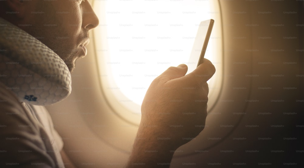 Man in airplane using smart phone. Space for copy. Close up.