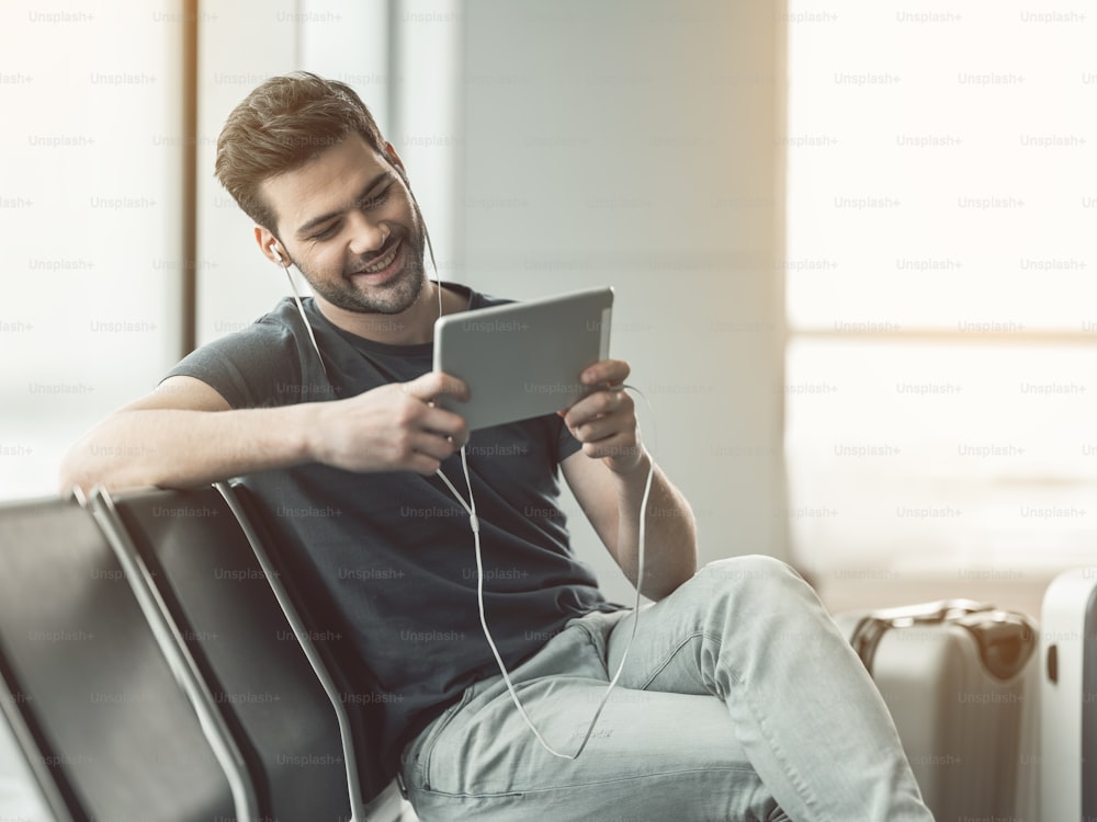 Portrait of cheerful bearded man hearing song while looking at electronic tablet. Satisfied male resting with gadget concept