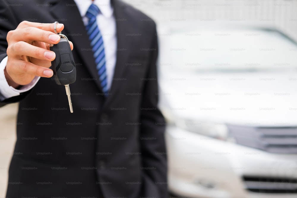 Businessman holding a car key on garage background. Buy Sale and Insurace the car concept.
