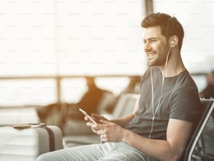 Retrato de un hombre riendo que escucha una canción con auriculares mientras usa un dispositivo digital. Concepto de ocio
